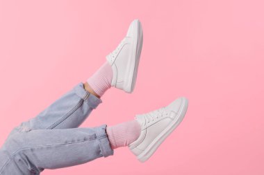 Pembe arka planda şık beyaz ayakkabılar giyen bir kadın, yakın plan. Metin için boşluk