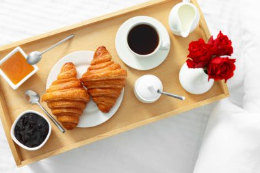 Yatakta servis edilen lezzetli kahvaltı. Taze kruvasan, kahve, bal ve reçel.