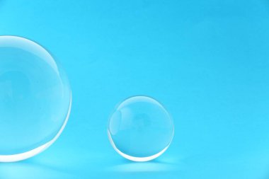 Açık mavi zemin üzerinde şeffaf cam toplar. Metin için boşluk