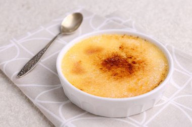 Lezzetli creme brulee kasede ve kaşık açık dokulu masa, yakın çekim