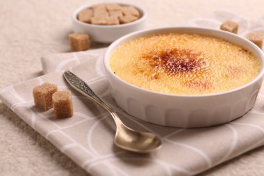 Lezzetli creme brulee kasede, şeker küpleri ve kaşık desenli masada, yakın çekim
