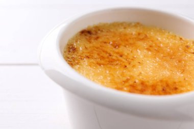 Lezzetli creme brulee kasede beyaz masada, yakın plan