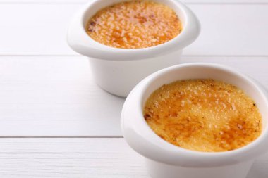 Beyaz ahşap masadaki kaselerde leziz krema brulee, yakın plan.