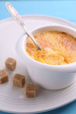 Açık mavi masada servis edilen kasedeki leziz creme brulee, yakından.