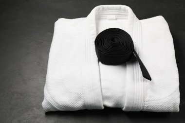 Black karate belt and white kimono on gray background clipart