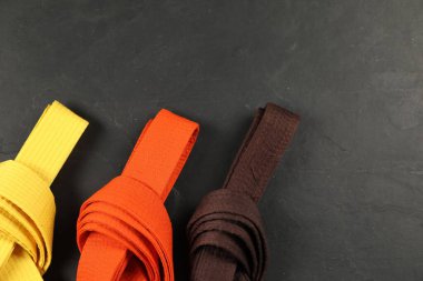 Colorful karate belts on gray background, flat lay. Space for text clipart