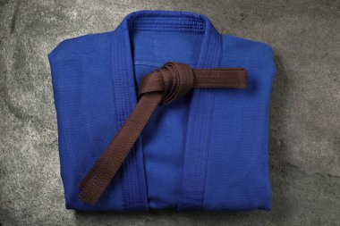 Kahverengi karate kemeri ve gri arka planda mavi kimono.