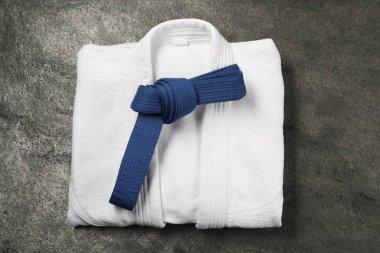 Mavi karate kemeri ve gri desenli arka planda beyaz kimono.