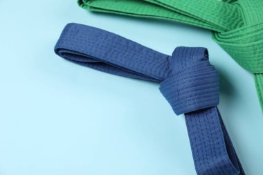 Açık mavi arkaplanda renkli karate kemerleri, metin için boşluk