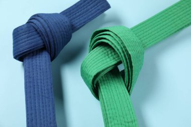 Açık mavi arkaplanda renkli karate kemerleri, yakın plan
