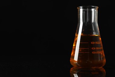 Siyah arka planda sarı yağlı cam matara, yakın plan. Metin için boşluk