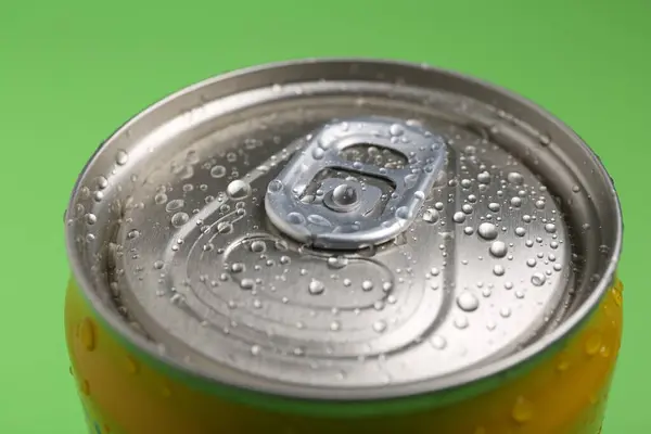 Energy drink in wet can on green background, closeup