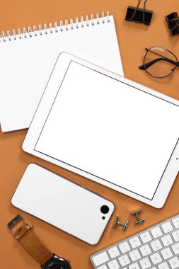 Kahverengi zemin üzerinde modern tablet bulunan düz kompozisyon. Metin için boşluk