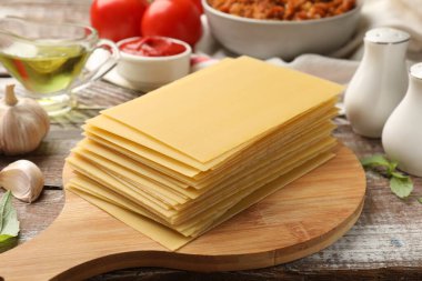 Ahşap kırsal masada lazanya pişirmek için makarna ve diğer ürünler yığını, yakın plan.