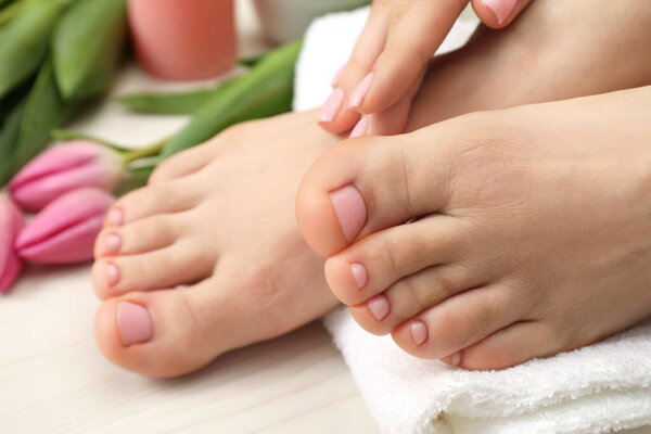 Woman with neat toenails after pedicure procedure on white wooden floor, closeup