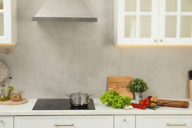 Yemek pişiriyorum. Mutfaktaki tezgahın üstünde taze sebze ve çömlek.