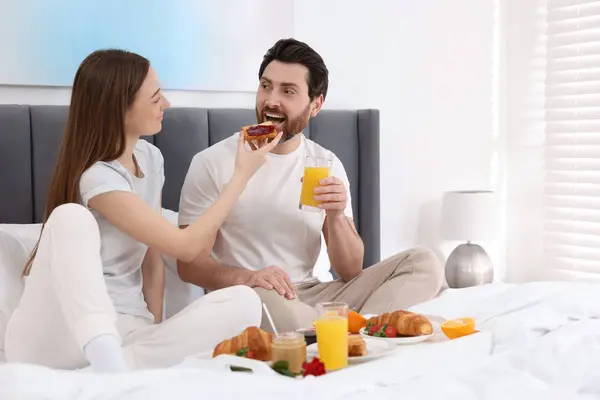 stock image Tasty breakfast. Wife feeding her husband on bed at home. Space for text