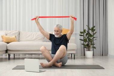 Son sınıf öğrencisi evde dizüstü bilgisayarın yanında spor yapıyor.