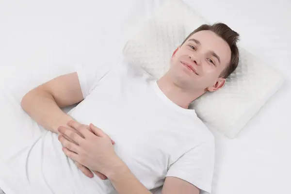 Man lying on orthopedic pillow in bed