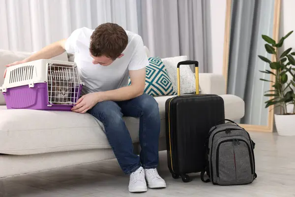Travel with pet. Man closing carrier with cat on sofa at home