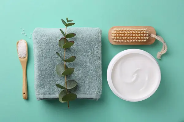 Jar of cream, body care products and eucalyptus branch on turquoise background, flat lay