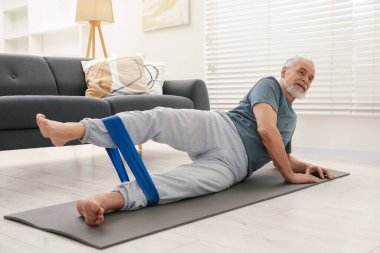 Son sınıf öğrencisi evde spor yaparken lastik bant takıyor.