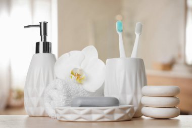 Banyo aksesuarları. Banyodaki ahşap masada farklı kişisel bakım ürünleri ve çiçek.