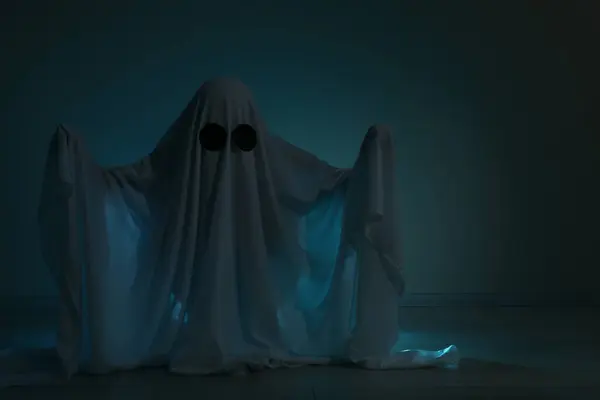 Creepy ghost. Woman covered with sheet on dark background, space for text