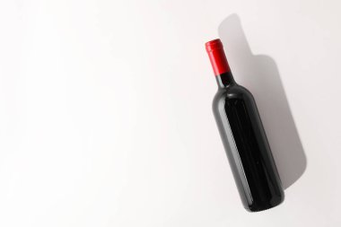 Beyaz arka planda bir şişe pahalı kırmızı şarap, üst manzara. Metin için boşluk