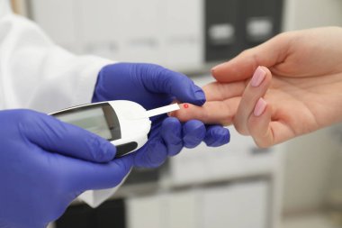 Diyabet. Doktor kan şekerini klinikte glukometreyle ölçüyor.