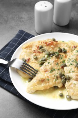 Delicious chicken piccata with herbs served on grey table clipart