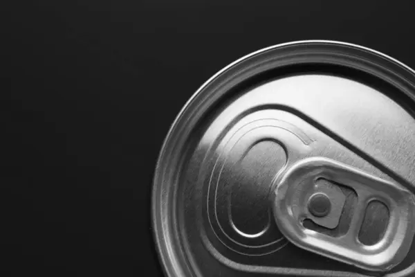 Energy drink in can on black background, top view. Space for text