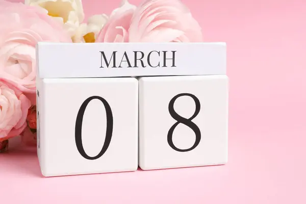 International Women\'s day - 8th of March. Wooden block calendar and beautiful flowers on pink background
