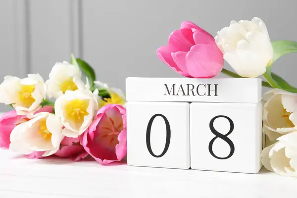 International Women\'s day - 8th of March. Wooden block calendar and beautiful flowers on white table