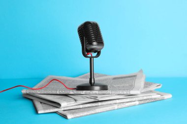 Gazeteler ve açık mavi arka planda klasik mikrofon. Gazeteci işi.