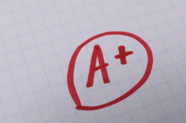 Okul derecesi. Not defteri kağıdında artı işareti olan kırmızı harf A, üst görünüm