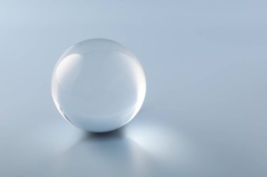 Açık gri arka planda şeffaf cam top. Metin için boşluk