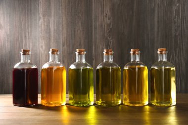 Sebze yağları. Ahşap masada cam şişelerde farklı yağlar var.