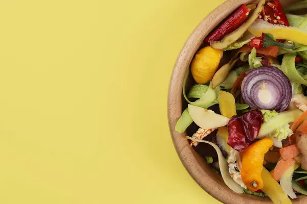 黄色の背景にボウルに新鮮な野菜の皮 トップビュー テキスト用スペース — ストック写真