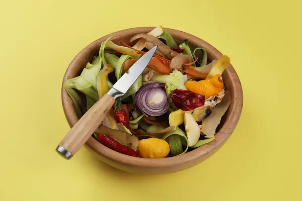 黄色の背景に新鮮な野菜とナイフのピール — ストック写真