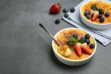 Lezzetli creme brulee kasede böğürtlen ve gri masada kaşık. Metin için boşluk