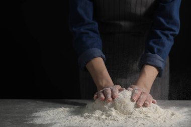 Ekmek yapıyorum. Masada hamur yoğuran bir kadın, yakın plan. Metin için boşluk