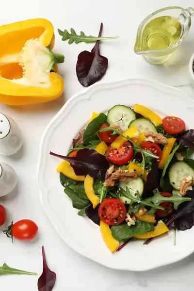 Tasty fresh vegetarian salad and ingredients on white marble table, flat lay