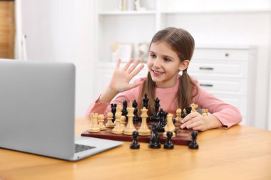 Evde online öğretmenle satranç oynamayı öğrenen tatlı bir kız.