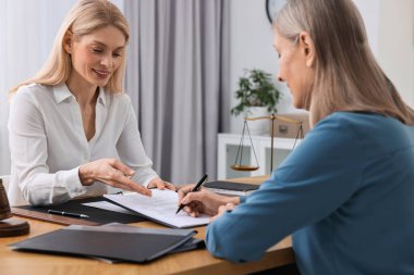 Üst düzey kadın avukatın ofisinde belge imzalıyor.