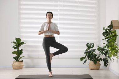 Yoga stüdyosunda hasırda ağaç asana pratiği yapan bir kız. Vrksasana pozu