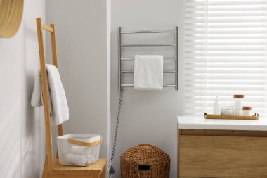 Banyodaki beyaz duvarda havluyla ısıtılmış tırabzan.