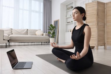 Evde online kanepe ile yoga dersi alan güzel bir kız.