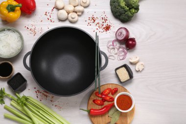 Wok, yemek çubukları ve beyaz ahşap masa üzerinde farklı ürünler, düz yatak. Metin için boşluk
