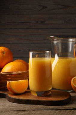 Lezzetli taze portakallar ve meyve suyu ahşap masada, yakın plan.